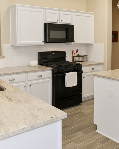 Modern kitchen with white cabinets, beige granite countertops, black appliances, subway tile backsplash, and a central island under warm lighting.